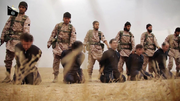 An image grab taken from a propaganda video released on November 16, 2014 by al-Furqan Media allegedly shows members of the Islamic State jihadist group preparing the simultaneous beheadings of at least 15 men described as Syrian military personnel. In the highly choreographed sequence, jihadists march the prisoners by a wooden box of long military knives, each taking one as they pass, before forcing their victims to kneel in a line and decapitating them. (C) AFP PHOTO